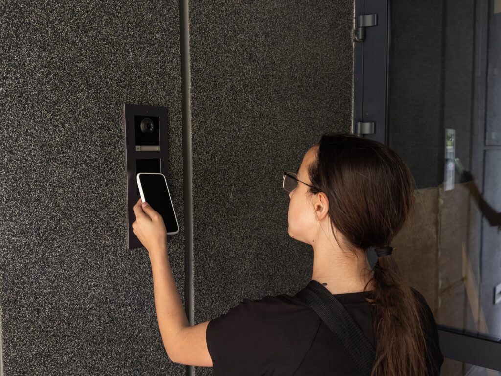 Smart home concept - close up of teenage girl use mobile phone to open electronic lock