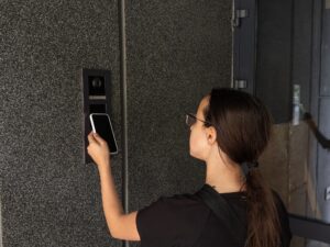 Smart home concept - close up of teenage girl use mobile phone to open electronic lock